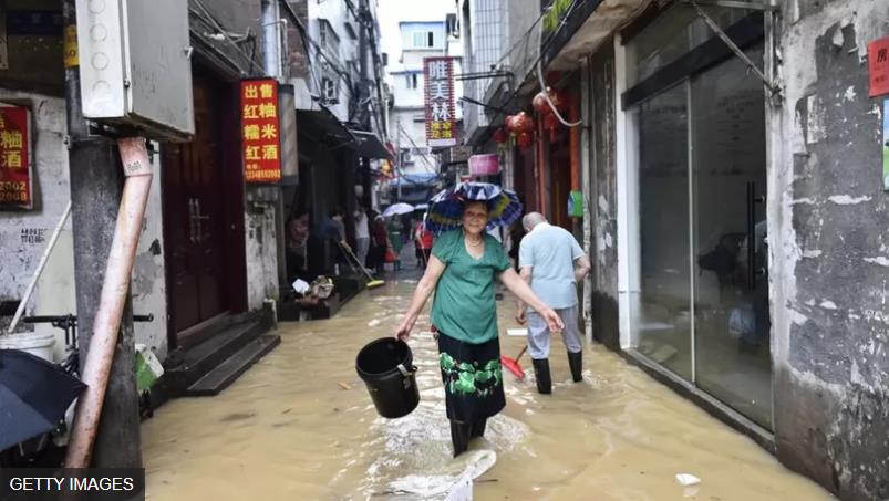 福建建瓯，一名妇女行过被洪水淹没的街道