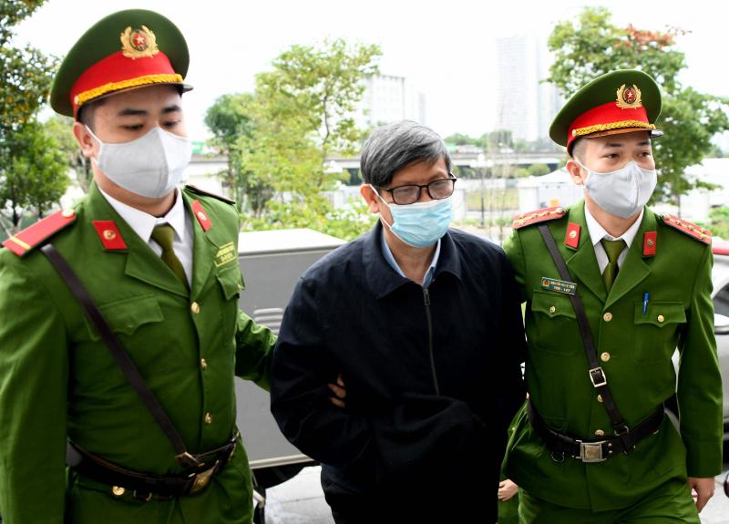 越南前卫生部长阮青龙（中）因冠病检测试剂盒受贿案在河内受审